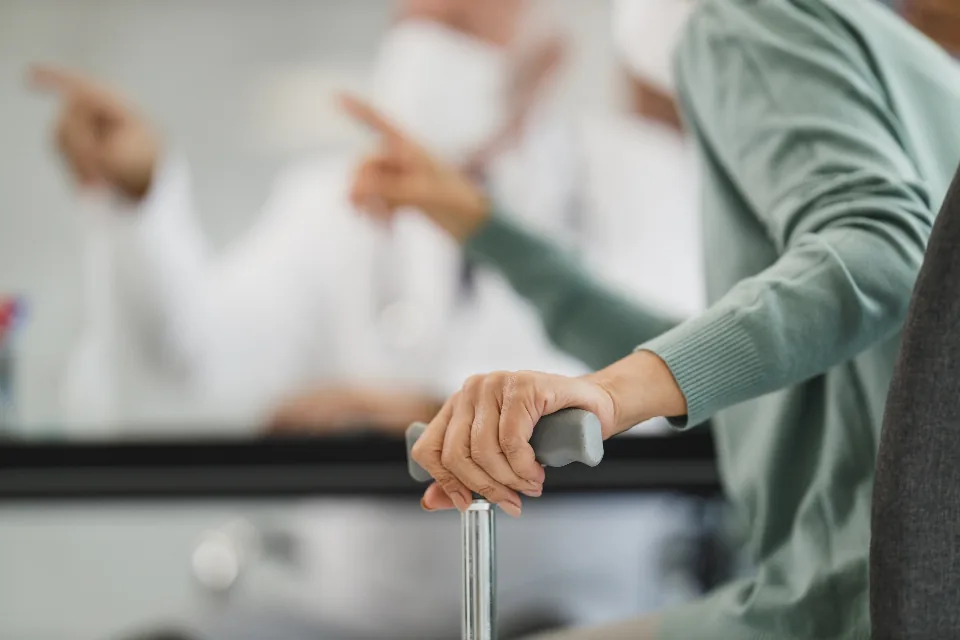 An older patient's hands resting on a walking cane
