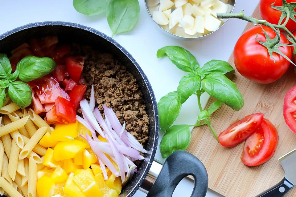 Fresh vegetables and pasta being prepared in a pan