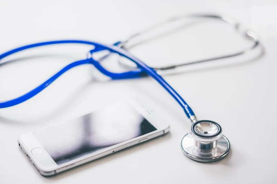 A stethoscope and a phone on a clinician's desk