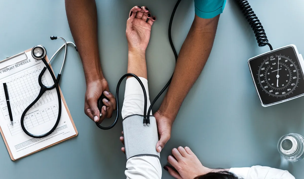 A blood pressure cuff being fitted to a patient's arm